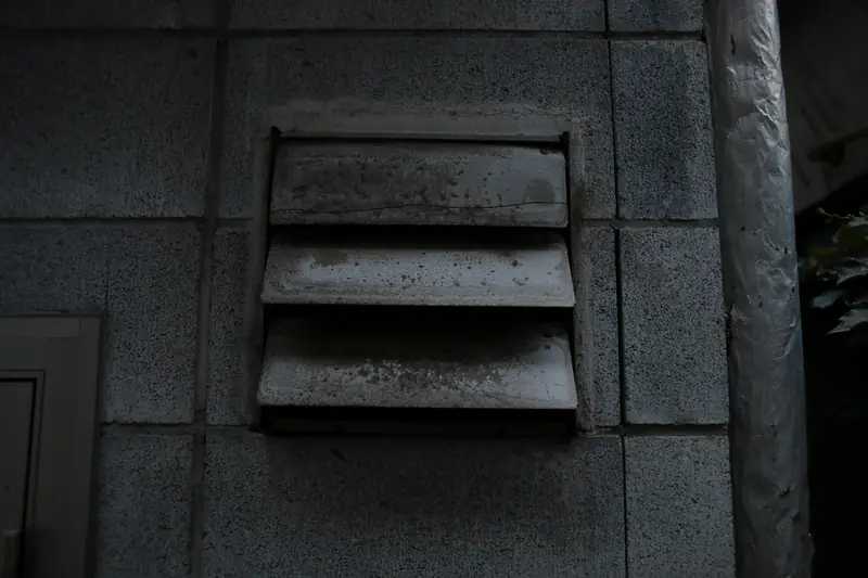 Louvered vent grille set into a dark stone wall